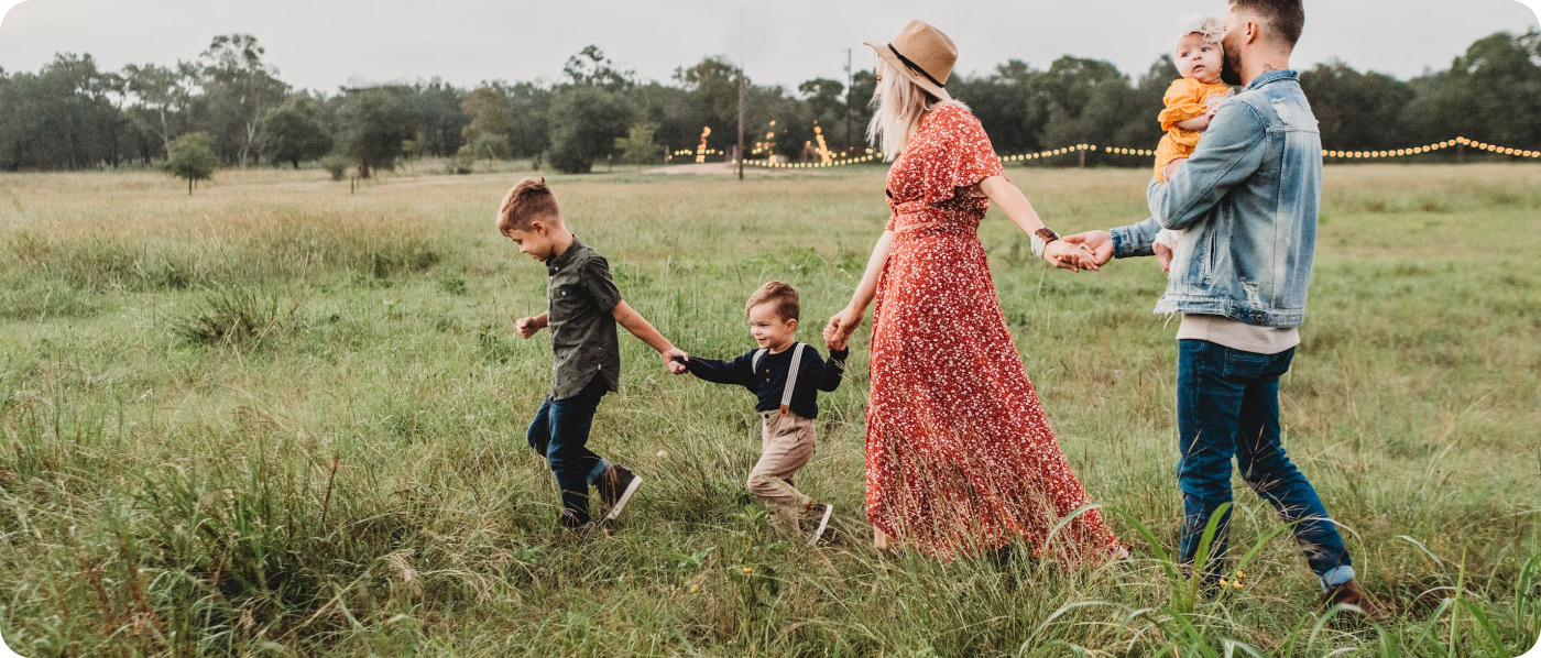 a family benefiting from ADHD therapy for children holding hands having fun in a field