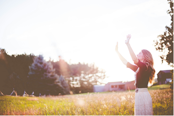 a female raising her arms feeling the warmth of the sun