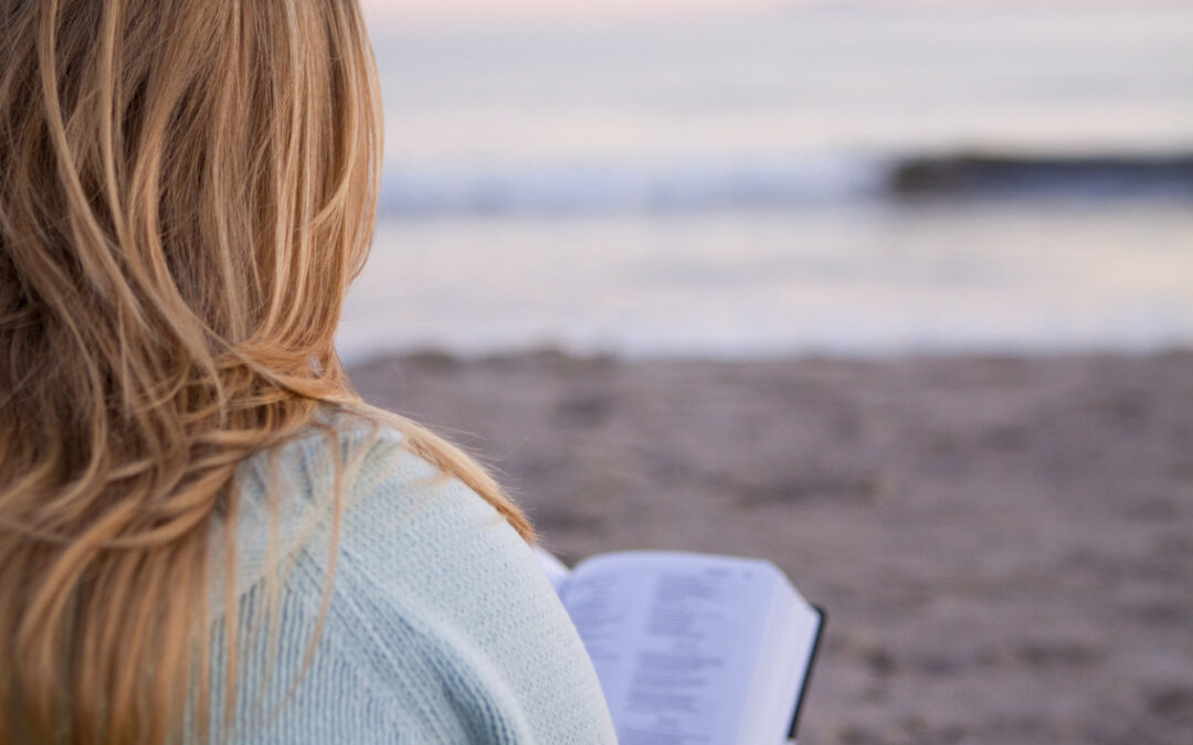 woman on the beach reading the bible to manage anxiety